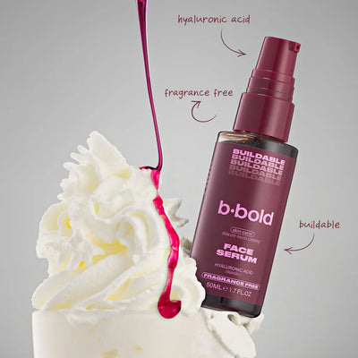 b-bold face serum bottle with whipped cream and pink liquid on a gray background
